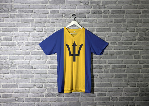 Barbados flag on shirt and hanging on the wall with brick pattern wallpaper.