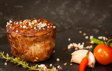 Delicious grilled filet of beef with tomatoes, chili pepper, garlig and thyme  on stone plate.