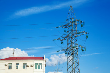 Apartment building with high voltage electric pylon transmitting electricity by wire. Power line...