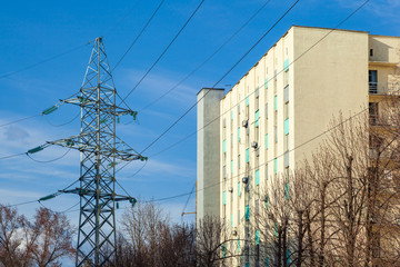 Apartment building with high voltage electric pylon transmitting electricity by wire. Power line...