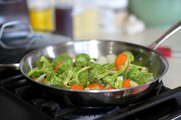 Stir fried vegetables cooking in a stainless steel pan.
