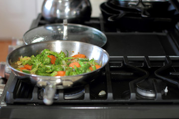 Stir fried vegetables cooking in a stainless steel pan.