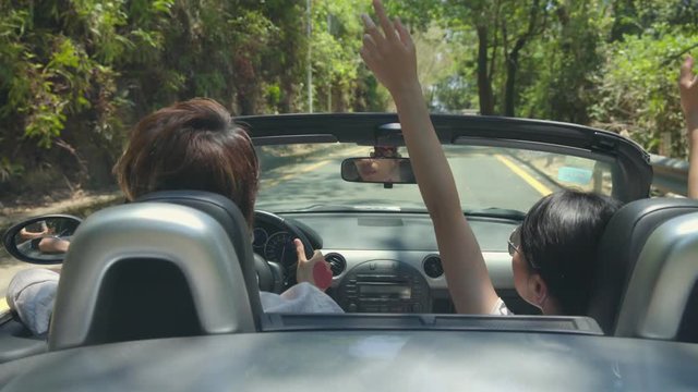 young asian couple having fun driving and riding in convertible sport car