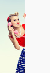 woman with phone, in pin-up style dress, showing blank signboard
