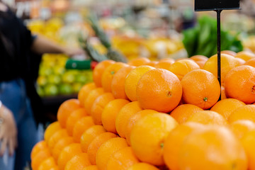 Woman hand choosing a tangerines or oranges at supermarket.