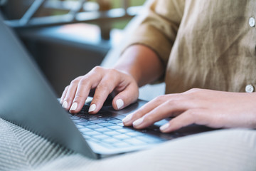 Closeup image of woman's hands using and typing on laptop keyboard