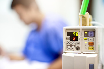 Selective focus to Infusion pumps with blurry patient play smart phone in hospital. The concept of...