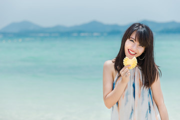 retty cool fashionable girl in the bright swimsuit, sunglasses, posing against the backdrop of the sea. In the hands holding a fruit.