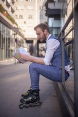 one young man siting while wearing inline skates and holding a notebook.