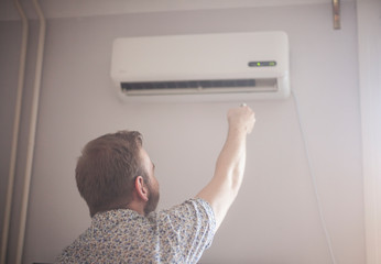 one young man turning on his air conditioner.