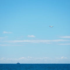 Fototapeta na wymiar Sea horizon and clear blue sky. Ship and plane on the horizon.