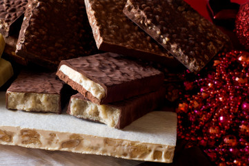 Turron. Typical Christmas food in Spain. Christmas tree decorations in the background. Selective focus.