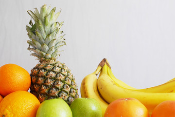 Fruit on a gray background. Food background. Pineapple, green apples, bananas and oranges.