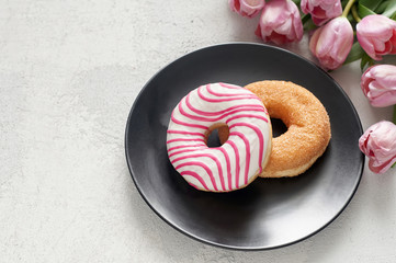 Sugar and Striped-glazed donuts with tulips on black plate