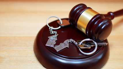 Judge gavel and key chain in shape of two splitted part of house on wooden background. Concept of...