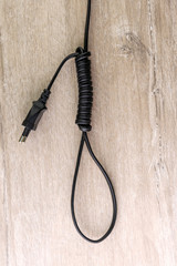 concept of energy dependence: hinge loop made of an electric cord with a plug, on a wooden background, selective focus