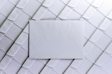 set of empty white envelopes lying in a row on a desk in the office, one envelope removed from the row and lying on the surface, short focus, toning