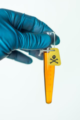 container with a poison in the scientist's hand, a yellow warning label with a skull and bones, on white, a short focus