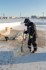 The installer splits the ice block with a crowbar