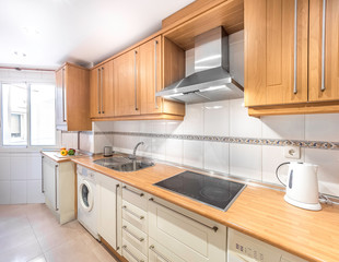 New stylish bright kitchen with wooden cabinets. Spacious modern fully equipped appliance interior with wooden desk, ceramic stove and  big windows