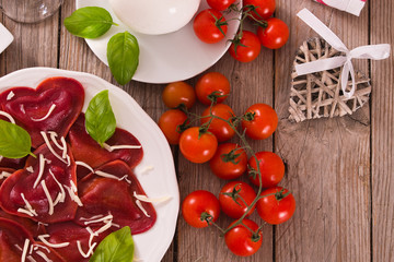 Red heart ravioli with tomato, mozzarella and basil.