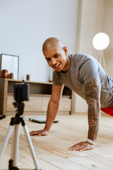 Dark-skinned sportsman showing exercises while making video