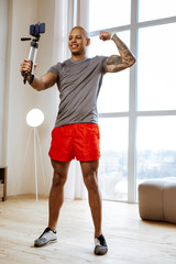 Fototapeta na wymiar Athletic man wearing red shorts making selfie showing his biceps