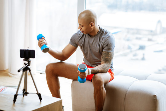 Sportsman showing exercises with dumbbells while filming blog