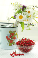 A bouquet of wildflowers and a glass bowl of red currant