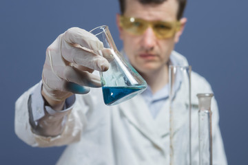 Glass bulb with chemical reagents in the hand of the laboratory assistant