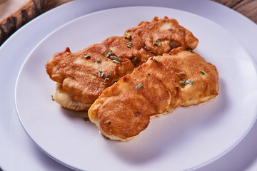 Deep-fried battered cod fillets, in a white plate on a wooden background. Close-up