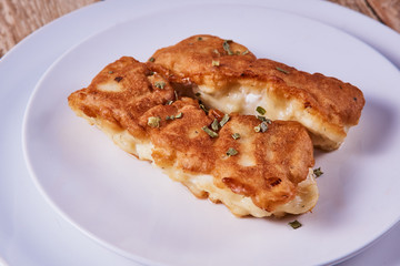 Deep-fried battered cod fillets, in a white plate on a wooden background. Close-up