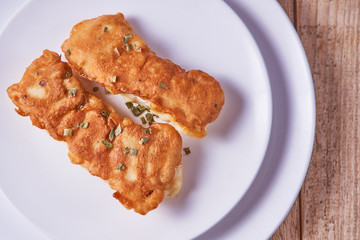 Deep-fried battered cod fillets, in a white plate on a wooden background. Flat lay