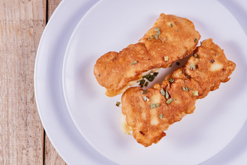 Deep-fried battered cod fillets, in a white plate on a wooden background. Flat lay, Light tone
