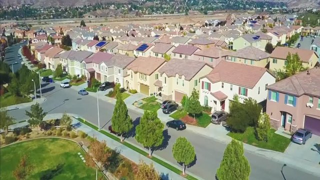 Aerial drone footage flying over a community of houses from a park.