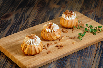 profiters with cream on a wooden substrate