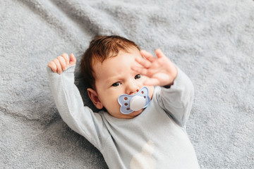 Portrait of baby boy angry, furious, frowning and agressive lying on a bed. Childrens emotions