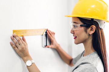 Young woman construction engineer in a yellow helmet working and  looking job for planning project at building home site