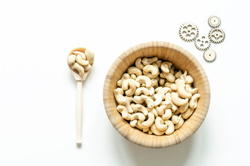 Wooden plate with cashew nuts. Wooden spoon and wooden parts of the mechanism. The concept of proper nutrition and healthy lifestyle. The free space of the white background.