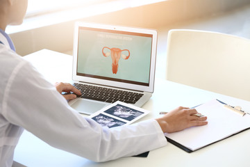 Young gynecologist with laptop working in her office