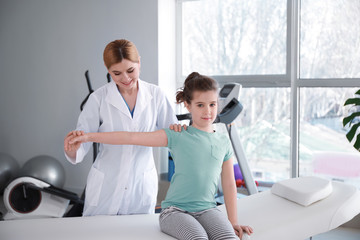 Physiotherapist working with little girl in rehabilitation center