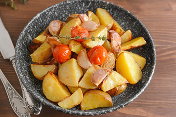 Plate with tasty baked potato on wooden table