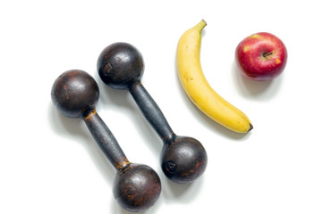 Two metal brutal dumbbells on a white background, top view close-up. Nearby lies an Apple and a banana, the concept of proper nutrition and a healthy lifestyle