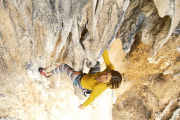The girl climbs the rock. Fitness in nature and rock climbing. The climber climbs up.