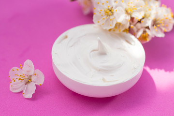 Obraz na płótnie Canvas face cream and apricot flowers pink background