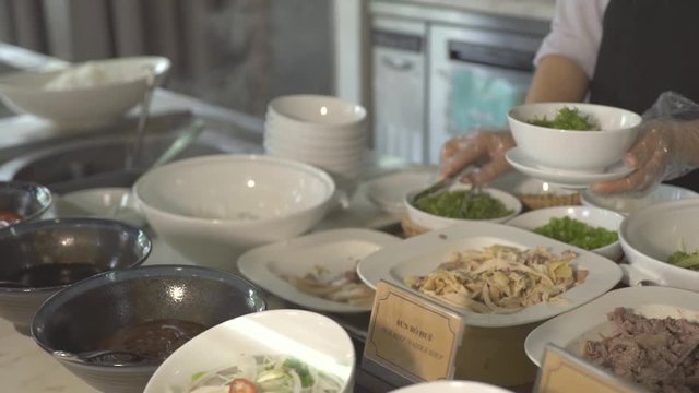 Cook putting food in bowl in buffet while lunch in all inclusive resort hotel restaurant. Restaurant food for traditional brunch, lunch and dinner in luxury hotel.