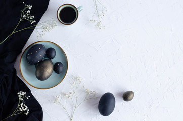 Easter flat lay with black eggs on a white background.