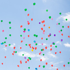 Many colorful balloons fly in the blue sky. Bright festive event. Blue sky and clouds