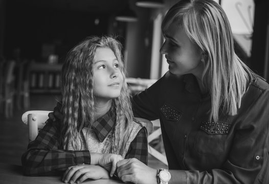 Portrait happy loving family, mother and daughter sitting in city cozy café and hugging. Mother and daughter smiling sincerely. Styling family, true emotions, good day 