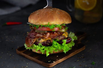 Homemade fresh beef burger on wooden board in dark mood photo style.